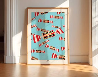May include: A framed art print featuring a light blue background with a pattern of red and white wrapped candies. The candies have the word "Caprice" in English and Arabic. The print is in a gold frame.