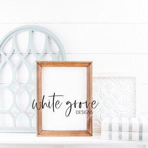 May include: A light wood frame with a white mat and a blank white canvas. The frame is sitting on a white shelf with a light blue decorative windowpane and a white tile with a floral design behind it. The text "white grove designs" is written in black cursive below the frame.