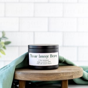May include: Black candle jar with a white label that says "Your Image Here" and "2 files included: High resolution JPEG, PSD with Smart Object". The candle jar is sitting on a wooden stand with a teal cloth draped over it.