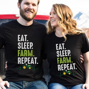 May include: Two people wearing black t-shirts with a green tractor graphic and the text "Eat. Sleep. Farm. Repeat."