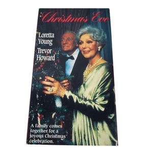 Puede incluir: Una cinta VHS vintage de la película "Christmas Eve" con Loretta Young y Trevor Howard. La portada tiene un fondo oscuro con el título en escritura roja y una foto de los actores. El texto dice "A family comes together for a joyous Christmas celebration."