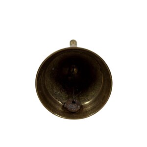 May include: A close-up shot of a brass bell, viewed from the inside. The bell has a rounded shape with a small loop at the top for hanging. The clapper is visible inside the bell. The bell has a shiny, golden appearance.