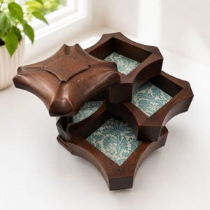 May include: A multi-tiered wooden storage box with a dark brown finish and a square, scalloped-edge design. The interior of each open compartment features a light blue and white floral patterned lining, with one lid resting partially open.