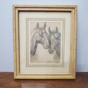 Może przedstawiać: Oprawiony rysunek ołówkiem przedstawiający dwa konie, których głowy są blisko siebie. Grafika znajduje się w kremowej ramie z teksturowanym wzorem. Konie są przedstawione w odcieniach szarości i czerni.