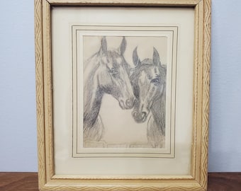May include: Framed pencil drawing of two horses, heads close together. The artwork is in a cream-colored frame with a textured pattern. The horses are depicted in shades of gray and black.