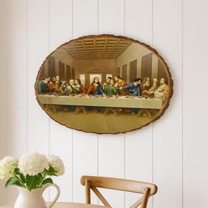 May include: A circular wooden wall hanging displaying a print of The Last Supper. The artwork shows the biblical scene with figures seated at a table. The wood has a natural, textured edge. It is mounted on a white wall.