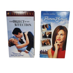 May include: Two VHS movie tapes. One is titled "The Object of My Affection" starring Jennifer Aniston and Paul Rudd. The other is titled "Picture Perfect" starring Jennifer Aniston and Kevin Bacon. Both tapes have colorful images.