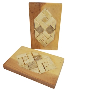 Pode incluir: Duas saboneteiras de madeira com um design geométrico. Cada saboneteira tem uma base retangular castanho claro com um mosaico de pedaços de sabão bege e castanho dispostos em forma de diamante. As saboneteiras são exibidas em um fundo branco.