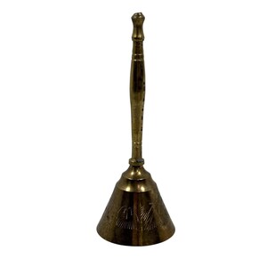May include: A tall brass hand bell featuring a long, slender handle with a rounded top and a flared base. The bell body is decorated with etched linear patterns around the circumference, showcasing a polished metallic gold finish.
