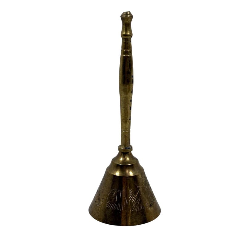May include: A tall brass hand bell featuring a long, slender handle with a rounded top and a flared base. The bell body is decorated with etched linear patterns around the circumference, showcasing a polished metallic gold finish.