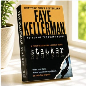 May include: A paperback book titled Stalker by Faye Kellerman, a New York Times bestseller. The cover features a yellow top section with black text, a black middle section with the title, and a torn bottom edge revealing a silhouette on a road.