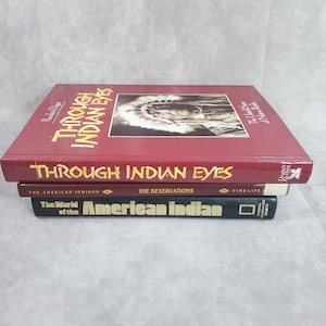 Może przedstawiać: Stos czterech książek z tytułami związanymi z kulturą Indian amerykańskich. Górna książka jest bordowa i nosi tytuł "THROUGH INDIAN EYES". Inne tytuły to "The American Indians" i "The World of the American Indian".