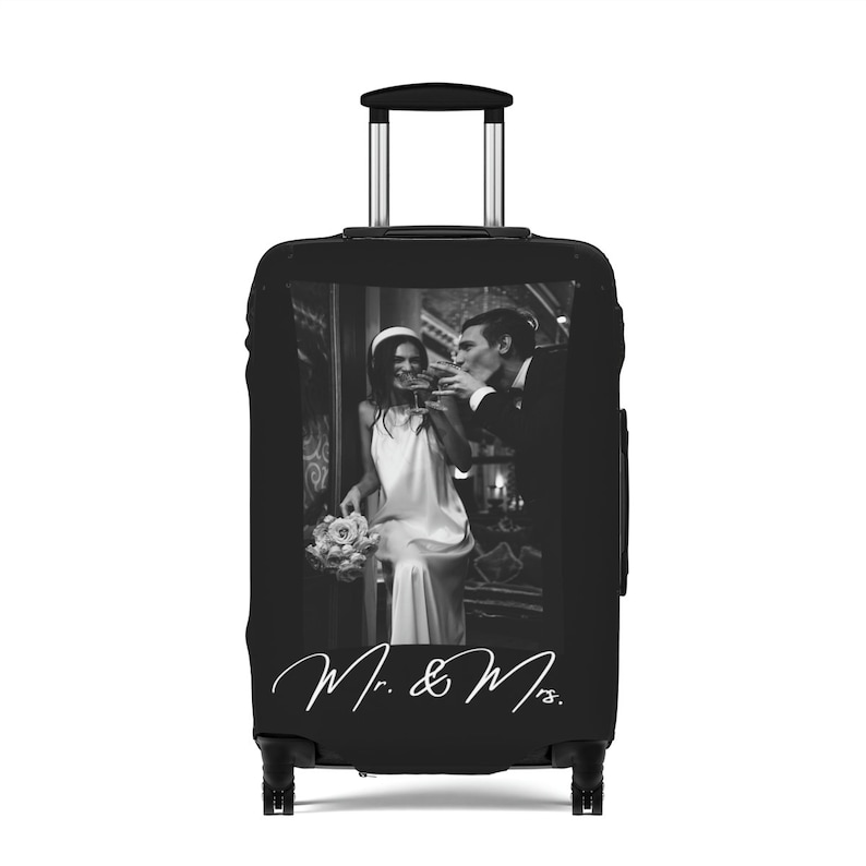May include: Black suitcase with a photo of a couple in black and white. The couple is toasting with drinks. The text "Mr. & Mrs." is written in white on the suitcase.