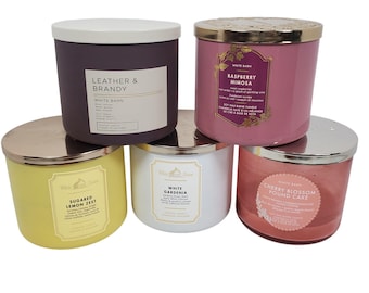 May include: Five scented candles with metal lids. The candles are in various colours, including purple, yellow, white, pink, and red. Each candle has a label with a different scent name, such as "Leather & Brandy" and "Raspberry Mimosa."