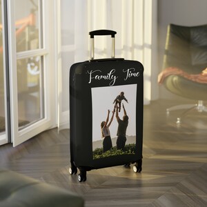 May include: Black suitcase cover with a photo of a family of three, a man, a woman, and a child, with the text "Family Time" printed on the front.