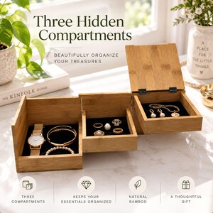 Op de afbeelding: Een driedelige sieradenorganizer van bamboe met een natuurlijke houten afwerking en zwarte fluwelen voering. De open vakken bevatten een gouden polshorloge, een gouden armband, een parelarmband en diverse ringen. Tekst: Three Hidden Compartments.