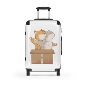 May include: White suitcase with a graphic of two cats in a cardboard box. The cats are facing each other and have their arms outstretched. The orange cat is on the left and the gray cat is on the right.