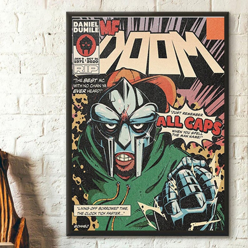 May include: A comic book cover featuring a green and silver masked character with the text "MF DOOM" in large red letters. The character is wearing a green hooded jacket and has a red and white baseball cap on. The text "ALL CAPS" is in a yellow speech bubble. The text "JUST REMEMBER" is in a smaller yellow speech bubble above the "ALL CAPS" speech bubble. The text "WHEN YOU SPELL THE MAN NAME!" is in a smaller yellow speech bubble below the "ALL CAPS" speech bubble.