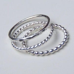 May include: A set of three silver stacking rings. The rings are different styles: one is hammered, one is beaded, and one is twisted.