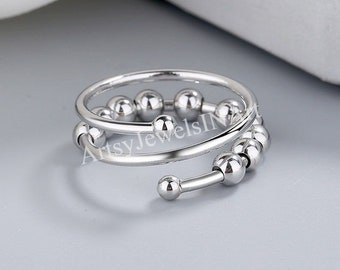 May include: A silver ring with a double band of small, round beads. The beads are arranged in a spiral pattern.