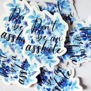 May include: A collection of stickers with a floral design in shades of blue. The stickers feature the phrase "Don't be an asshole" in black script. The floral design includes roses and other flowers.