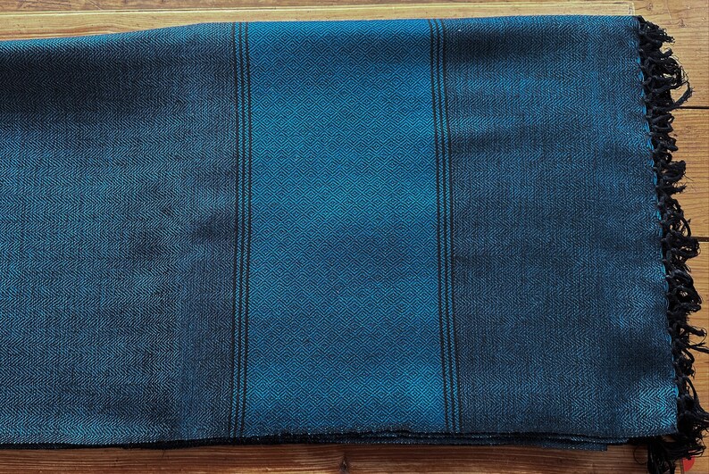Peut inclure: Une couverture en laine ray&eacute;e bleue et noire avec une bordure frang&eacute;e.