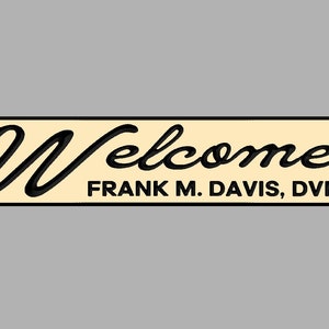 May include: A cream-colored sign with black lettering that reads "Welcome Frank M. Davis, DVM".