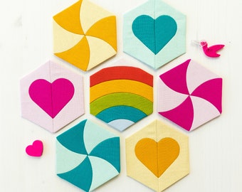 May include: Six colorful fabric coasters in a honeycomb pattern. The coasters feature different designs, including hearts, swirls, and rainbows. The coasters are made of a soft, textured fabric.