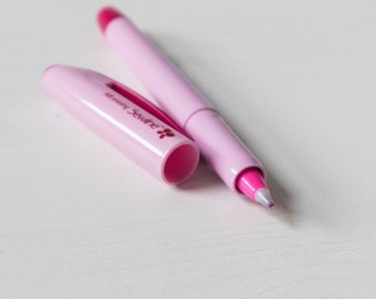 May include: A pink Sewline air-erasing pen with a matching cap. The pen's tip is a vibrant magenta, and the cap is off. The pen's body is a soft pink, and the text "Air erasing Sewline" is printed on the cap.