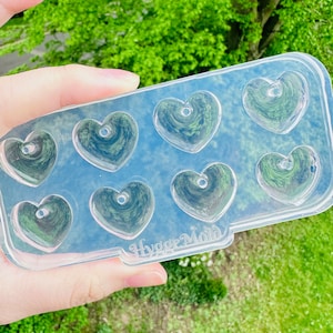 May include: Clear plastic mold with eight heart-shaped cavities. The mold is labeled "Hygge Mold".