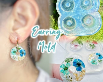 Könnte beinhalten: Eine transparente Silikonform zum Herstellen von Resin-Ohrringen. Die Form hat vier runde Vertiefungen mit einem Loch in der Mitte. Die Form ist mit "Earrings Mold" beschriftet.