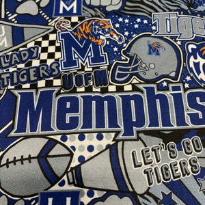 May include: A blue and gray fabric with a repeated pattern of the University of Memphis logo, a tiger, a football helmet, and the words "Lady Tigers", "U of M", "Memphis", and "Let's Go Tigers".