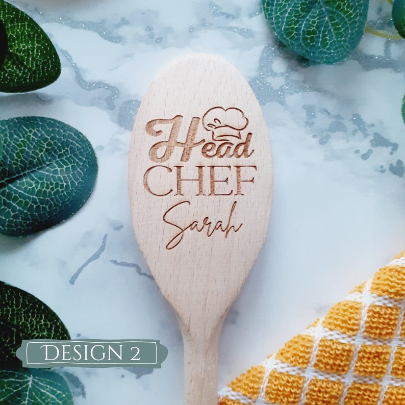 May include: Wooden spoon with the text "Head Chef Sarah" engraved on it. The spoon is light brown and has a chef's hat icon above the text.
