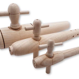 May include: Three wooden spigots of different sizes are displayed against a white backdrop. Each spigot features a cylindrical body and a handle with a crossbar. The wood has a light, natural colour.