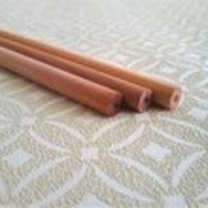 May include: Three wooden dowels of varying lengths and diameters. The dowels are natural wood colour and have a smooth, polished finish.