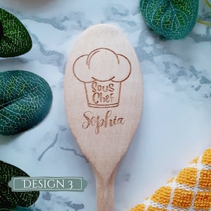 May include: A wooden spoon with the words "Sous Chef" and "Sophia" engraved on it. The spoon is decorated with a chef's hat.
