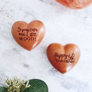 Peut inclure: Deux ornements en bois en forme de cœur avec des messages gravés. Le premier cœur dit "5 ans plus tard et je t'aime toujours WOOD!" Le deuxième cœur dit "Joyeux 5e anniversaire".