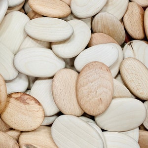 Puede incluir: Primer plano de una pila de piedras de madera lisas, de forma ovalada, en varios tonos de marr&oacute;n y beige.