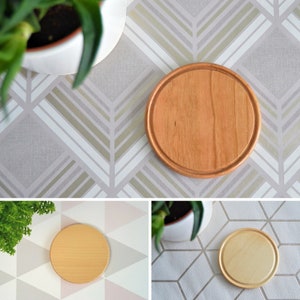 May include: Three round wooden coasters in a light brown colour. The coasters are on different patterned surfaces.