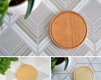 May include: Three round wooden coasters with a light brown color. The coasters are on different patterned surfaces.