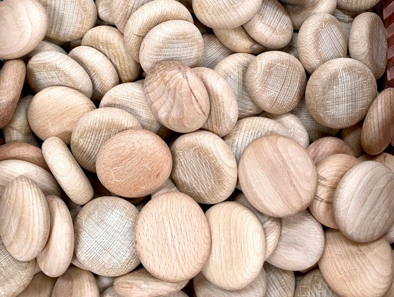Puede incluir: Primer plano de una pila de discos de madera lisos de color marr&oacute;n claro. Los discos son todos de tama&ntilde;o y forma similares, y est&aacute;n dispuestos en un patr&oacute;n aleatorio.