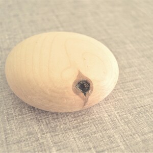 Puede incluir: Una esfera de madera marr&oacute;n claro con un peque&ntilde;o agujero en el centro.