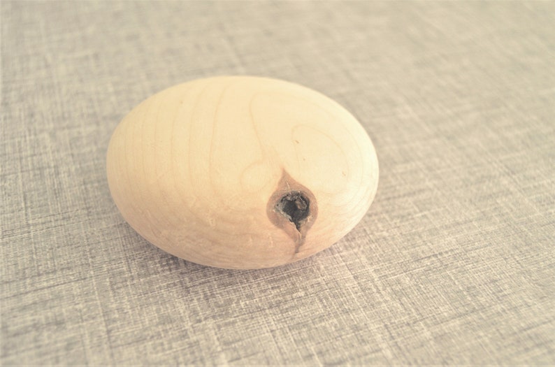 Puede incluir: Una esfera de madera marr&oacute;n claro con un peque&ntilde;o agujero en el centro.