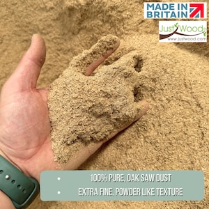 Może przedstawiać: Ręka trzymająca stos drobnego, jasnobrązowego trocin z dębu. Trociny są w 100% czyste i mają konsystencję proszku. W tle widoczny jest tekst "MADE IN BRITAIN" i "Just Wood".
