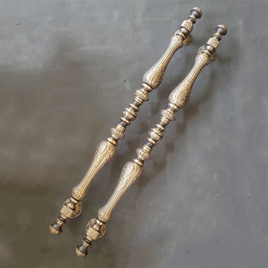 May include: Two ornate gold door handles with intricate designs. The handles are made of metal and have a polished finish.