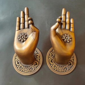 May include: Two ornate brass door handles shaped like hands in a prayer position. Each handle features a decorative floral design and intricate details.