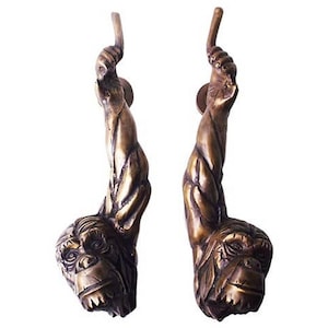 Può includere: Un paio di maniglie per porte in bronzo a forma di braccio e testa di scimmia. Le maniglie sono dettagliate e realistiche.