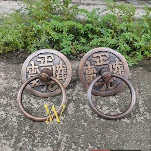 May include: Two antique-style bronze door handles with a ring pull. Each handle features a circular plate with Chinese characters and a raised design.