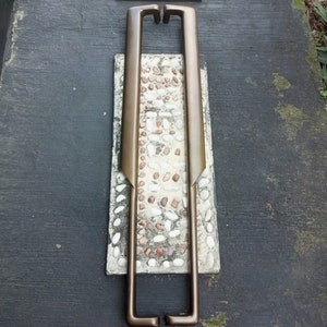 May include: A pair of antique bronze door handles with a rectangular shape and a simple design. The handles are mounted on a white tiled background.