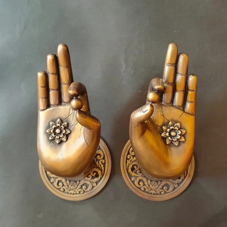 May include: Two ornate brass door handles shaped like hands in a prayer position. Each handle features a detailed floral design and a small bead at the tip of each finger.
